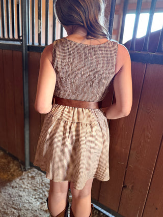 Person wearing a patterned dress with a belt in an indoor setting