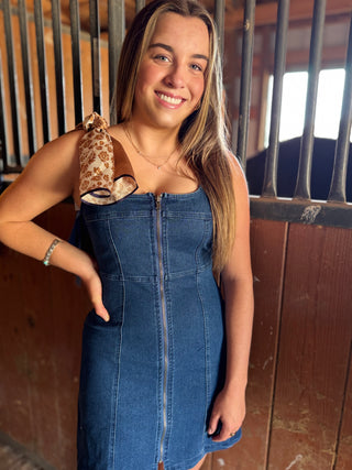 Woman in a blue denim dress standing in a stable