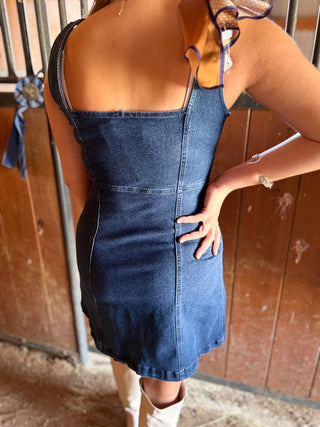 Person wearing a blue denim dress with a wooden background