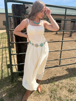 Woman in a white dress standing next to a metal fence in an outdoor setting