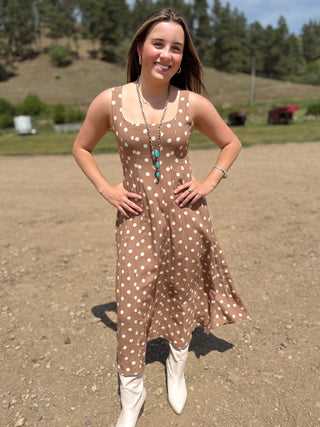 Woman in a polka dot dress standing outdoors with a scenic background