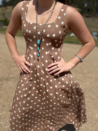 Woman wearing a brown dress with white polka dots outdoors
