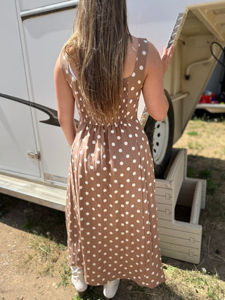 Woman in a polka dot dress standing next to an open trailer with a tire inside.