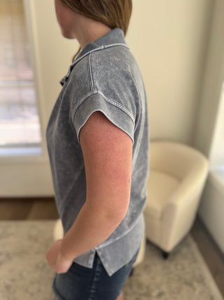 Lady wearing a charcoal grey half zip cap sleeve top.