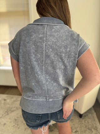 Lady wearing a charcoal grey half zip cap sleeve top.