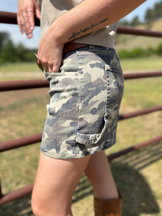 Person wearing camouflage shorts with a blurred natural background