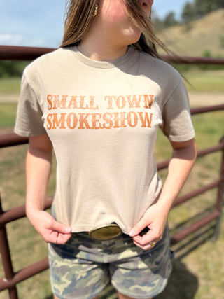 Person wearing a 'Small Town Smokeshow' t-shirt in an outdoor setting.