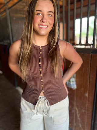 Woman wearing a brown ribbed tank top with buttons in an indoor setting