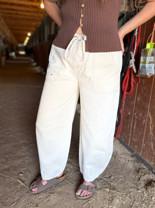 Person wearing a brown top and white pants in an indoor setting