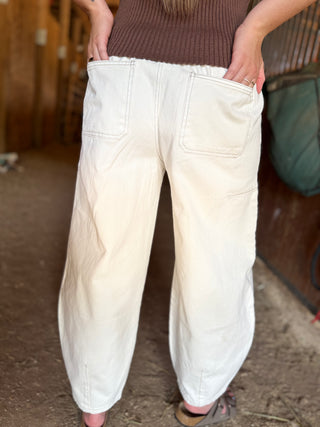 Person wearing white pants in an indoor setting with wooden walls.