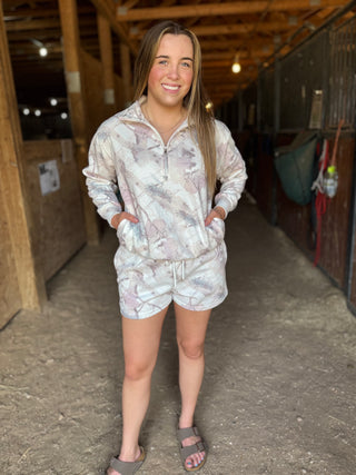 Woman wearing a patterned outfit standing in a barn.