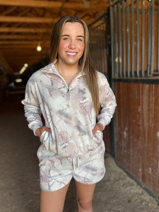 Woman wearing a patterned hoodie and shorts set in an indoor setting