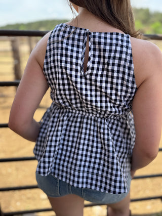 Person wearing a black and white checkered top with a blurred outdoor background