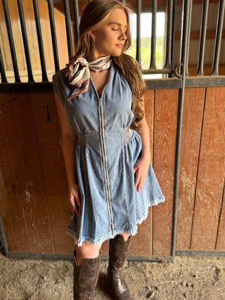 Woman in a denim dress standing in a stable