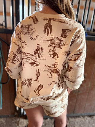 Child wearing a long-sleeve shirt with cowboy-themed graphics in a casual setting.