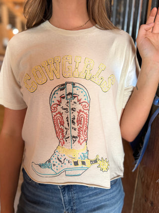 Person wearing a t-shirt with a cowboy boot graphic and 'Cowgirls' text.