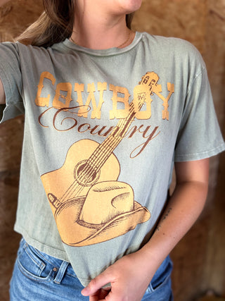 Person wearing a t-shirt with a graphic of a guitar, cowboy hat, and 'Cowboy Country' text.