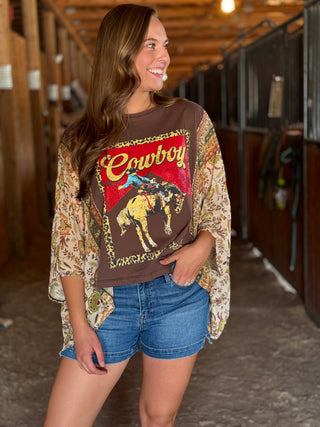 Woman wearing a cowboy-themed shirt with a horse graphic in a barn setting