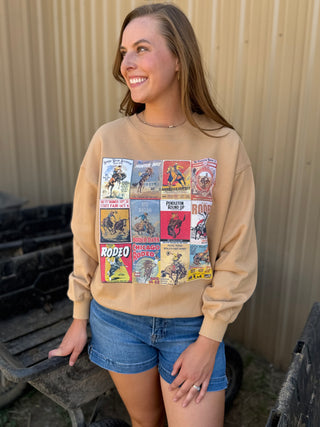 Woman wearing a beige sweatshirt with vintage rodeo posters, standing outdoors.