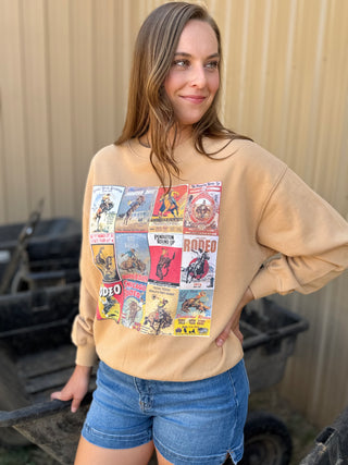 Woman wearing a beige sweatshirt with graphic designs, standing outdoors.