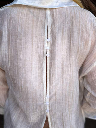 Close-up of a beige textured garment with a button detail.