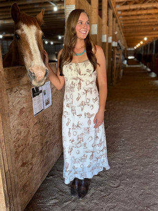 Woman in a dress standing next to a horse in a stable