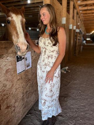 Woman in a patterned dress interacting with a horse in a stable.