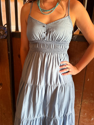 Woman wearing a light blue dress with a wooden background