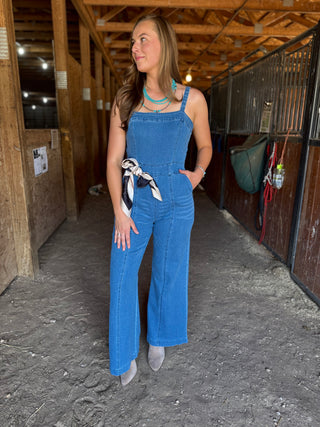 Woman wearing blue overalls standing in a stable.