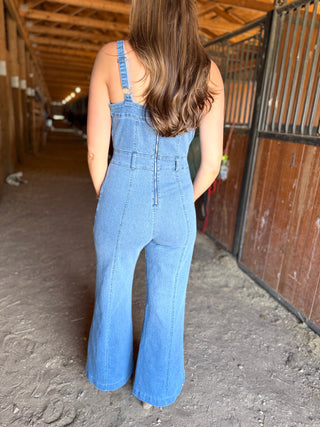 Person wearing blue denim overalls standing in a barn.