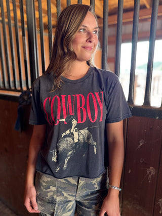 Person wearing a t-shirt with a graphic design and text, standing in an indoor setting.