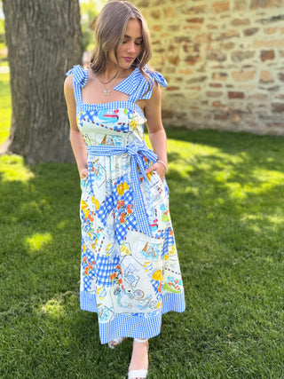 Woman wearing a colorful dress with a pattern of various designs standing outdoors.