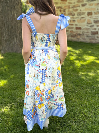 Person wearing a colorful dress with a pattern of vintage cars on grass.
