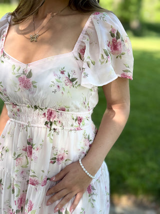 Woman wearing a white floral dress with a blurred green background