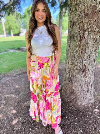 Woman in a floral dress standing next to a tree in a park