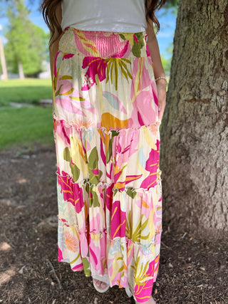 Person wearing a colorful floral dress standing next to a tree in an outdoor setting