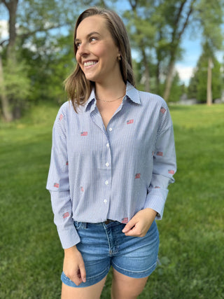 Woman wearing a blue striped shirt with small flags in a park setting