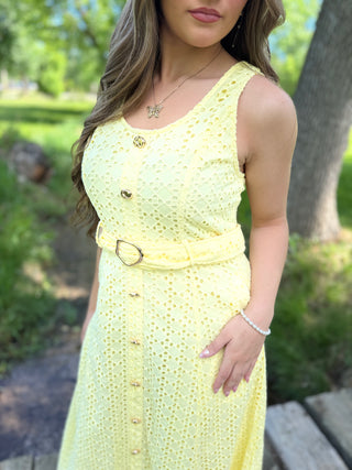 Woman wearing a yellow dress with a belt in an outdoor setting