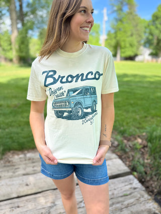 Person wearing a 'Bronco' t-shirt with a graphic of an old-style Bronco truck outdoors.