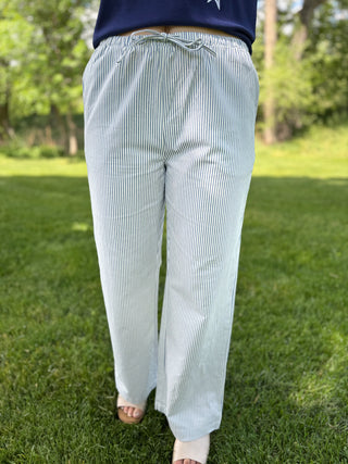 Person wearing light blue striped pants standing on grass with a blurred background
