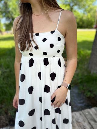 Girl standing outside wearing a black and white polka dot flowy dress.