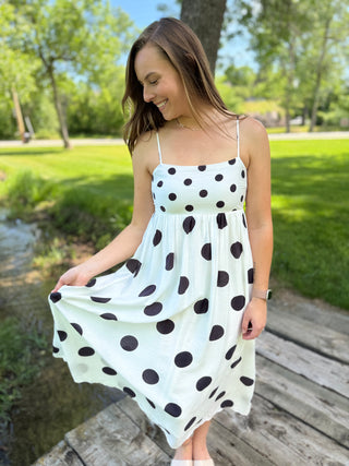 Girl standing outside wearing a black and white polka dot flowy dress.