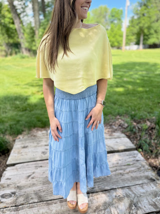 Woman wearing a yellow poncho top.
