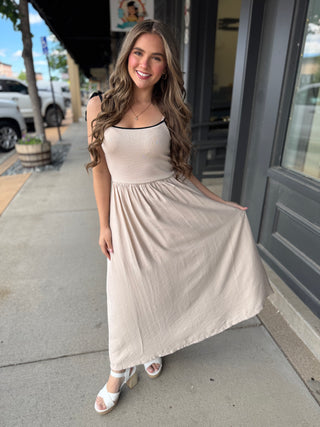 Woman in a beige dress standing on a sidewalk