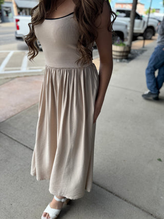 Woman wearing a beige dress on a sidewalk with a blurred background