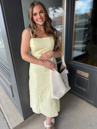 Woman in a light yellow dress standing outside a building