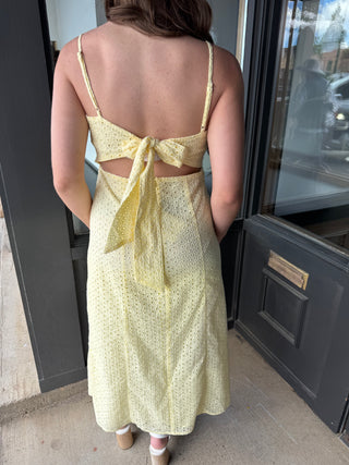 Person wearing a yellow dress with cut-out back standing in front of a door.