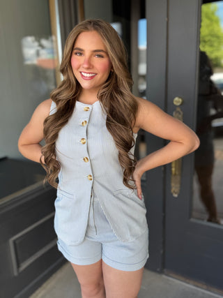 Woman in light blue outfit standing in front of a door