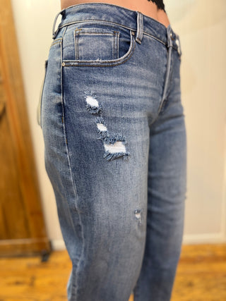 Ripped blue jeans being worn indoors with a neutral background