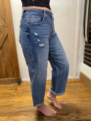 Person wearing blue jeans with a lace top in a room with wooden flooring.